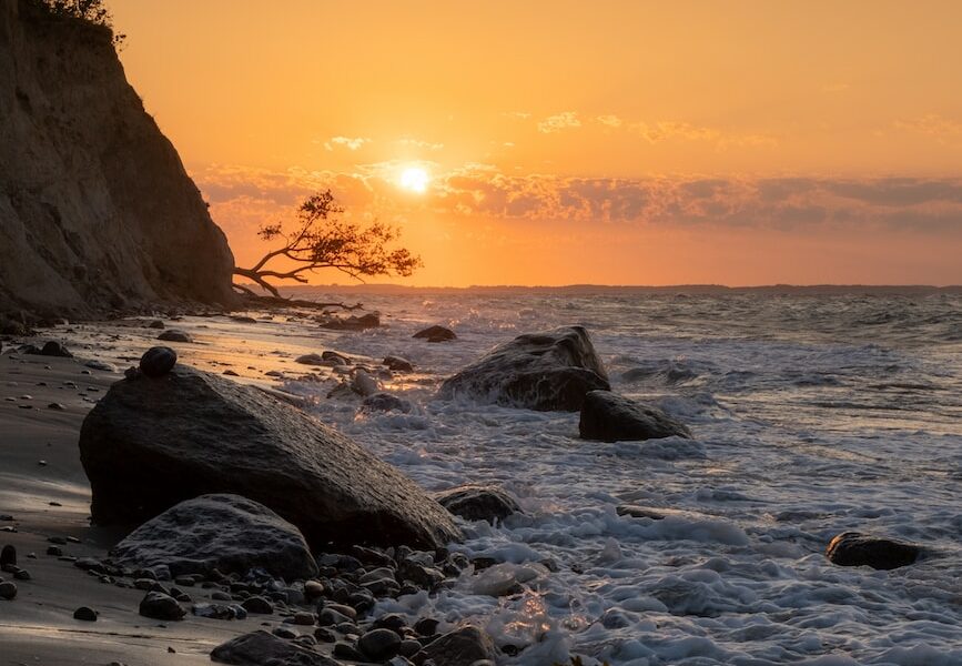 the sun is setting over the water at the beach